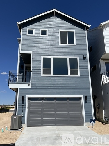 A two-story house with a garage door and balcony.