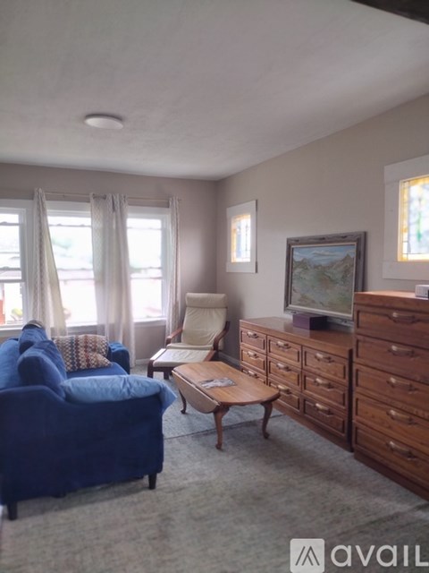 A living room with a blue couch, a wooden coffee table, and a painting on the wall.