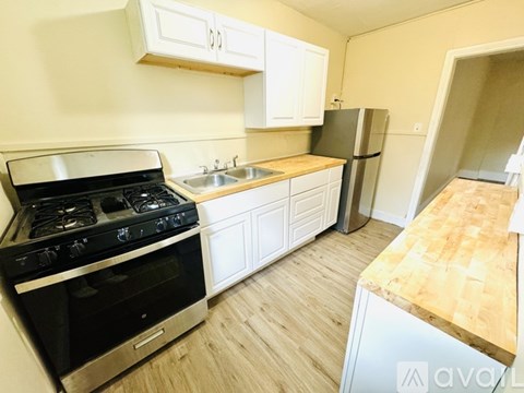 A kitchen with a black stove top oven, white cabinets, and a wooden countertop.