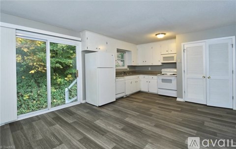 A kitchen with white cabinets and a grey floor.