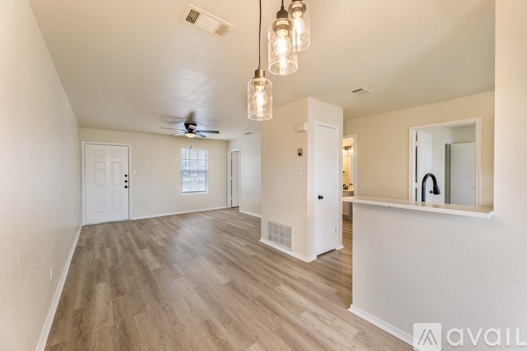 A spacious room with wooden flooring and a ceiling fan.