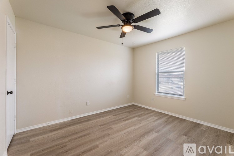 A room with a ceiling fan and a window with blinds.