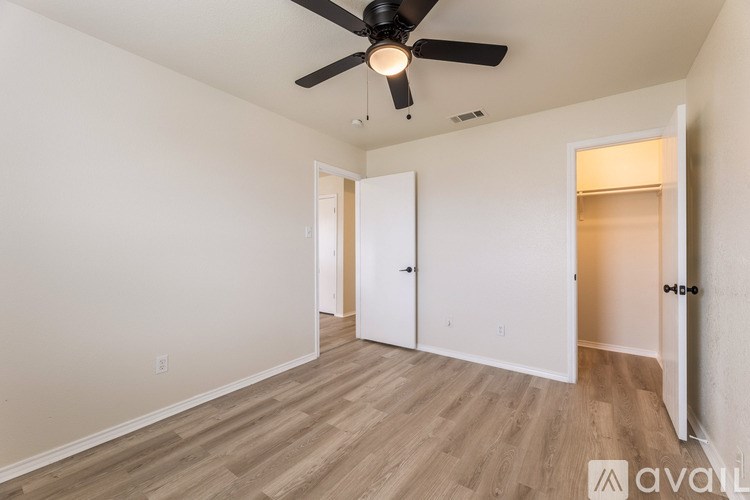 A room with a ceiling fan and wooden flooring.