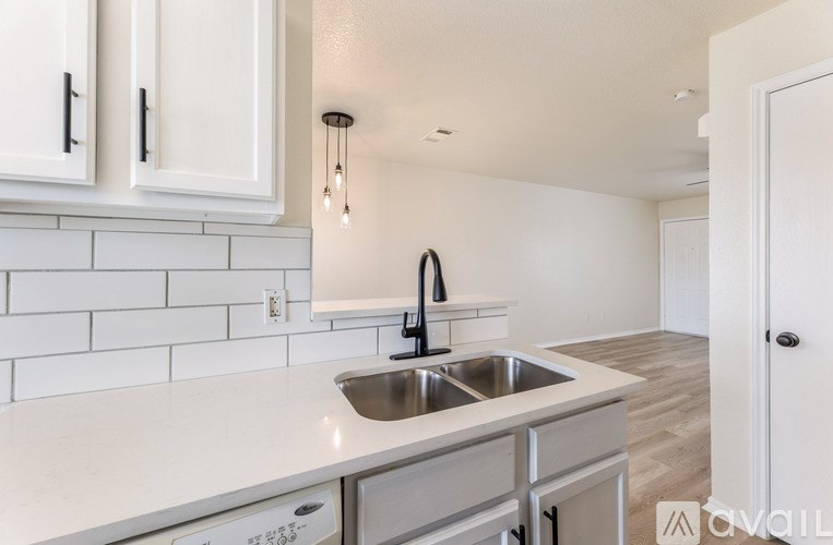 A kitchen with white cabinets and a stainless steel sink.