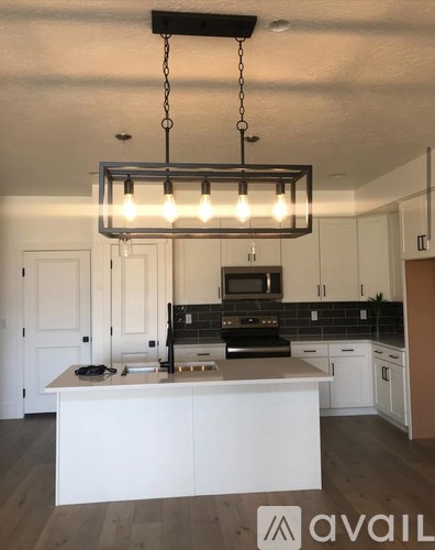 A kitchen with a white island and a hanging light fixture.