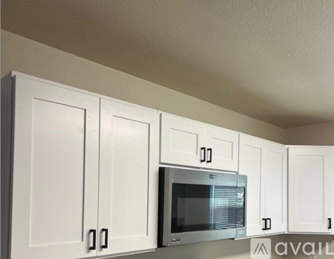 A kitchen with white cabinets and a microwave.
