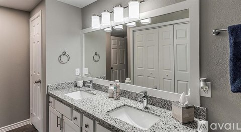 A bathroom with a granite countertop and a large mirror above the double sink.