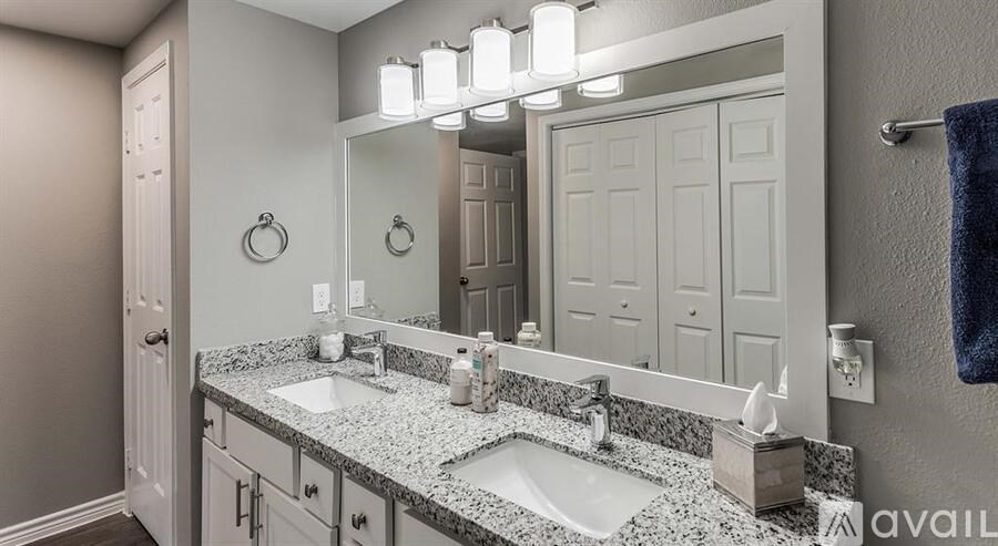 A bathroom with a granite countertop and a large mirror above the double sink.