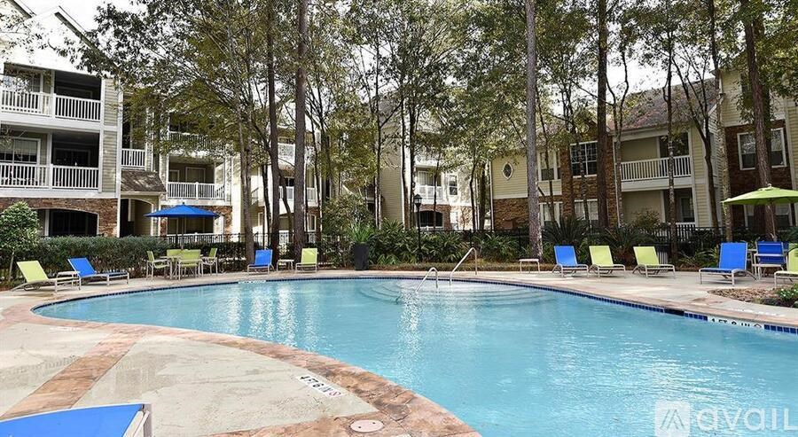 A pool surrounded by trees and chairs with umbrellas.