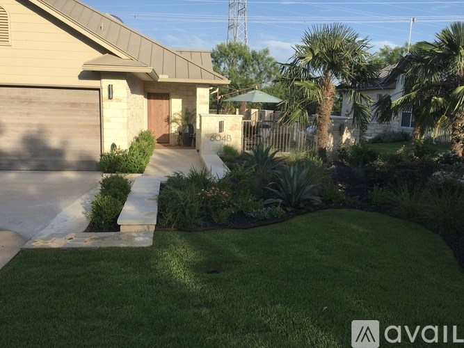 A house with a driveway and a palm tree in front.