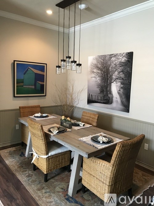 A dining room with a table set for two and a painting hanging on the wall.