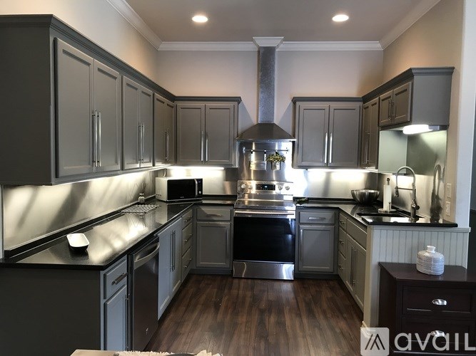 A modern kitchen with dark wood floors and grey cabinets.