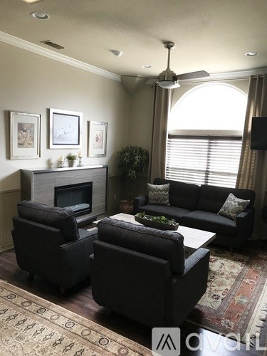 A living room with a fireplace, two couches, and a rug.