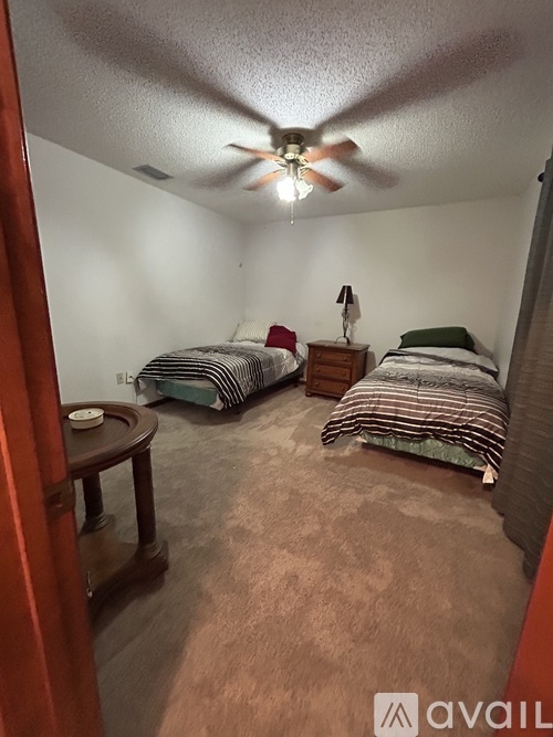 A bedroom with two beds and a ceiling fan.