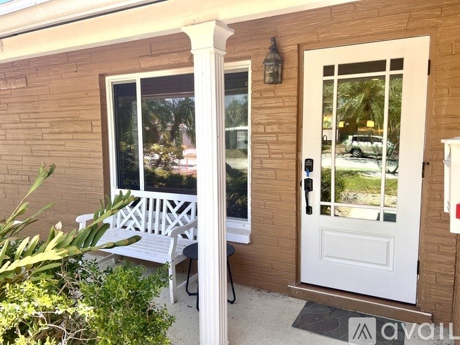 A white door and window with a bench outside a house.