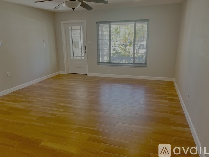A room with wooden flooring and a window showing a view of trees.