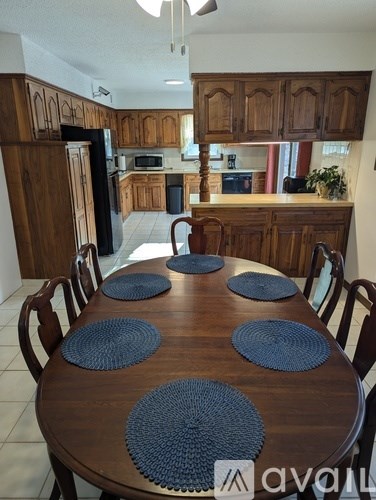 A kitchen with a table set for six with blue placemats.