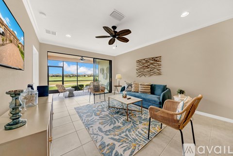 A living room with a ceiling fan and a view of the outdoors through the windows.