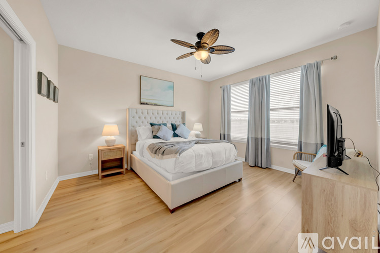 A bedroom with a large bed, a ceiling fan, and a television.