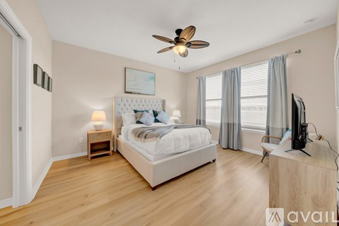 A bedroom with a large bed, a ceiling fan, and a television.