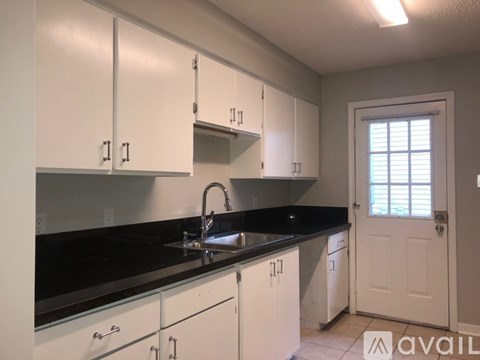 A kitchen with white cabinets and black countertops.