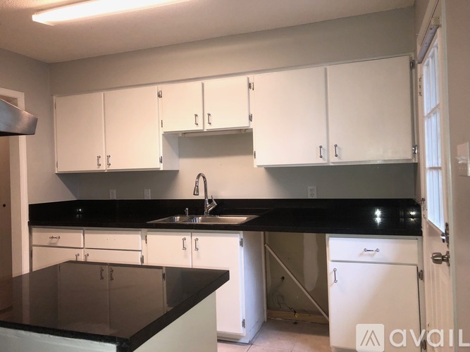 A kitchen with white cabinets and a black countertop.