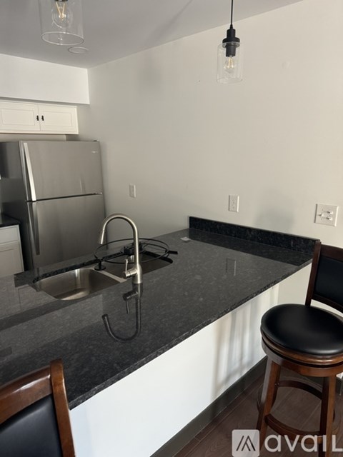 A kitchen with a granite countertop and a stainless steel refrigerator.