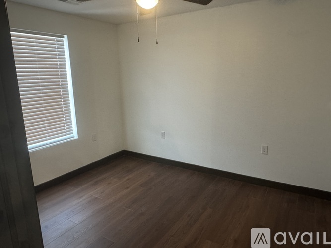 A room with wooden flooring and a window with blinds.