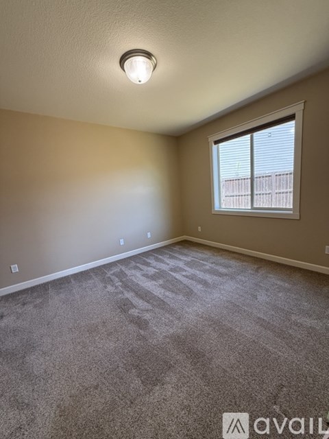 A room with a carpeted floor and a window with blinds.