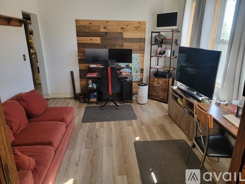 A living room with a red couch and a wooden wall.