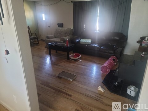 A living room with a black couch and a wooden floor.