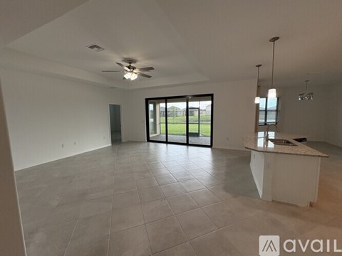 A spacious room with a ceiling fan and a kitchen island.
