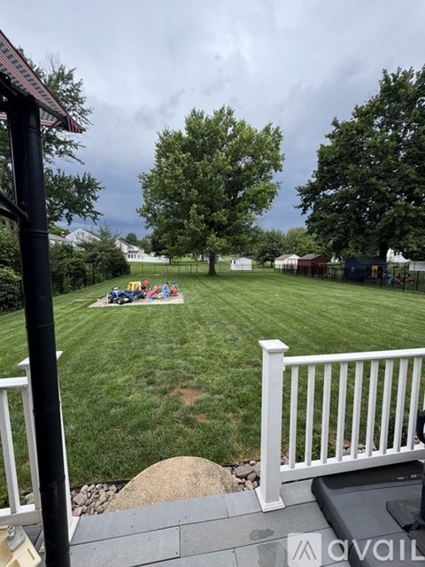 A backyard with a white fence and a family sitting on the grass.