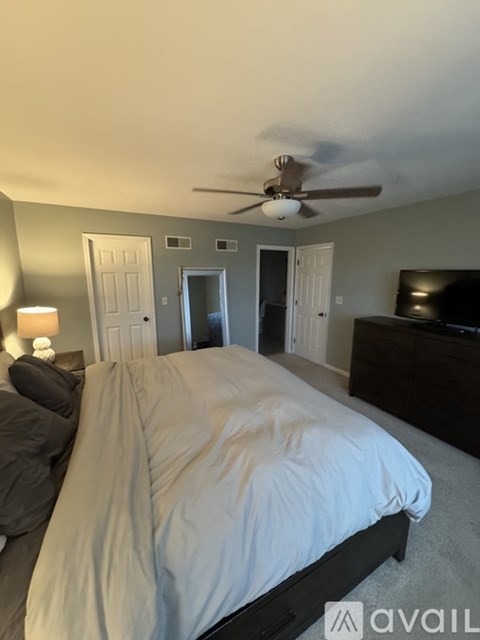A bedroom with a large bed and a ceiling fan.