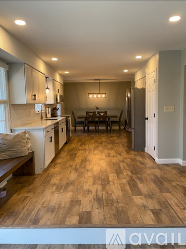 A kitchen with wooden floors and a dining table with chairs.