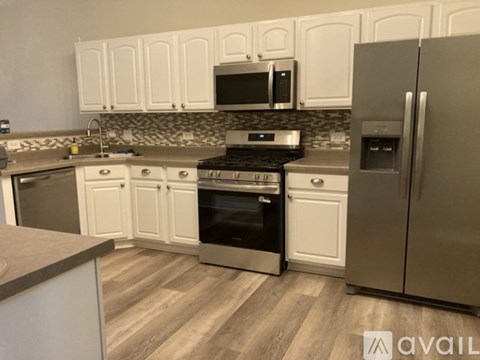 A kitchen with white cabinets and a stainless steel refrigerator.