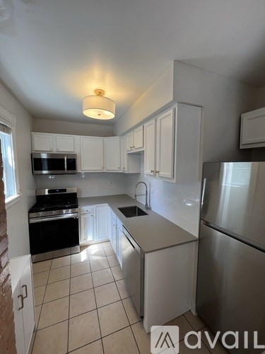 A kitchen with white cabinets and a stainless steel refrigerator.