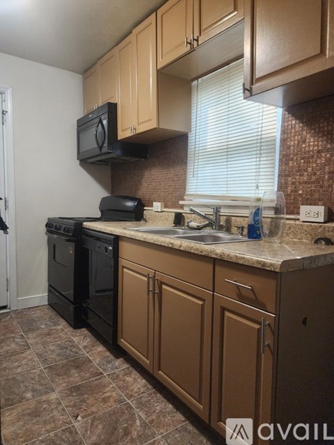 A kitchen with brown cabinets and black appliances.