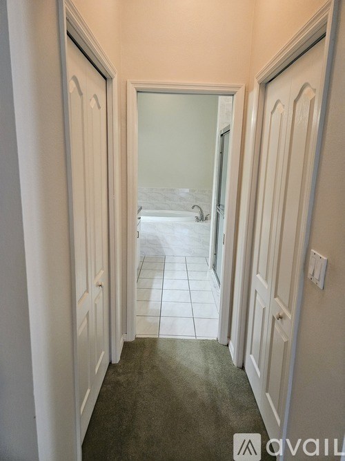 A hallway with white doors and a carpeted floor.