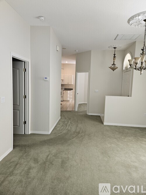 A room with a grey carpet and a chandelier.