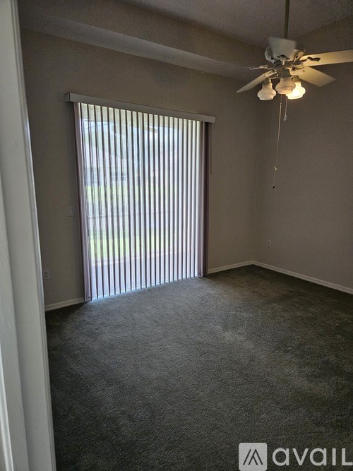 A room with a ceiling fan and a window with blinds.
