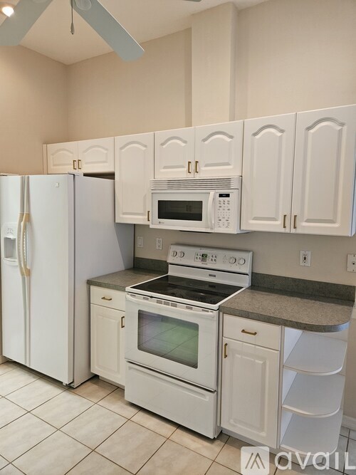 A white kitchen with a refrigerator, microwave, oven, and cabinets.