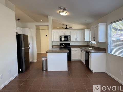 A kitchen with white cabinets and brown flooring.