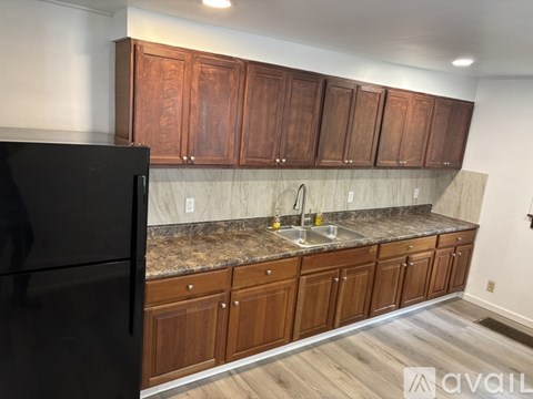 A kitchen with wooden cabinets and a black refrigerator.