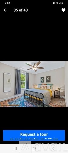 A bedroom with a bed, a ceiling fan, and a window with curtains.