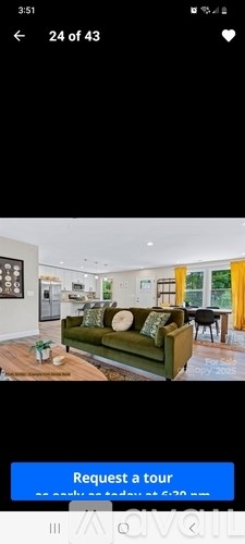 A living room with a green couch and a blue 'Request a tour' button.