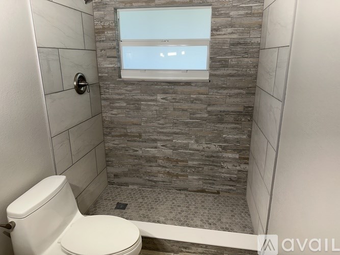 A bathroom with a toilet, tiled walls, and a window.