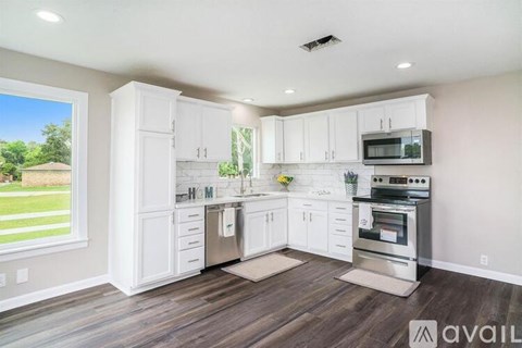 A kitchen with white cabinets and a wooden floor.