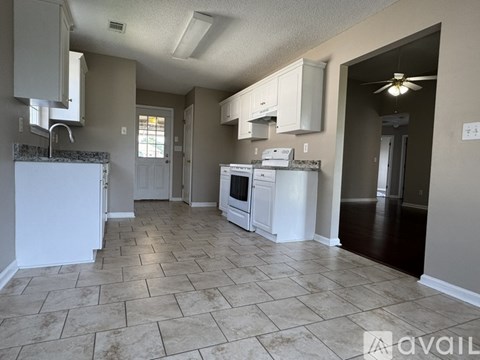 A kitchen with white appliances and a tiled floor.