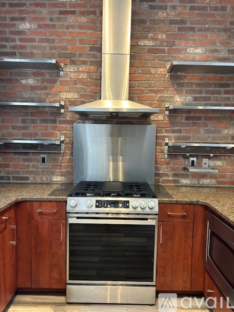 A stainless steel range hood is above a stove in a kitchen.